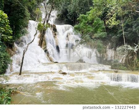 waterfall cascading through lush tropical jungle, surrounded by mist and greenery. The powerful flow of water creates a tranquil and awe-inspiring natural scene in untouched paradise 132227443