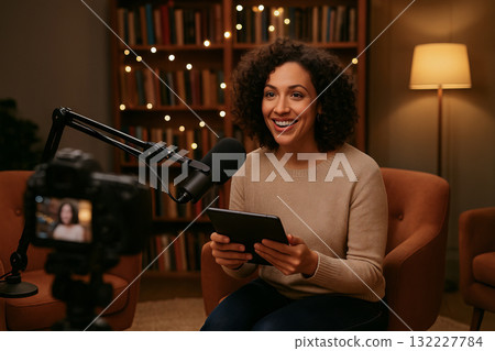 African american woman hosting talk show in cozy studio setting with warm lighting and decorative bookshelves African american woman hosting talk show in cozy studio setting with warm lighting and decorative bookshelves 132227784