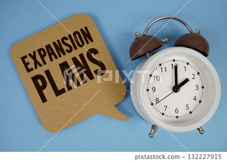 Expansion Plans text with alarm clock on blue background 132227915