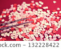 Heart-shaped topping sugar picked with tweezers. Stylish and cute background decoration. Feelings. Confectionery ingredients. 132228422