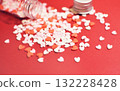 Heart-shaped sugar topping spilling from a small bottle. Cute background decoration. Overflowing feelings. Confectionery ingredients. 132228428