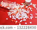 Heart-shaped sugar topping spilling from a small bottle. Cute background decoration. Overflowing feelings. Confectionery ingredients. 132228430
