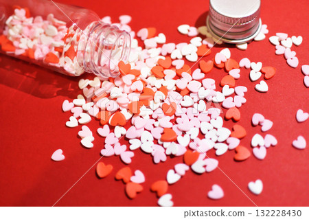 心形糖粒從小瓶子裡溢出。可愛的背景裝飾。滿滿的感動。糖果的配料。 132228430