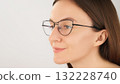 Confident woman with eyeglasses displays clear vision and focus, set against a neutral background with soft lighting, highlighting her features and expression. Copy space 132228740