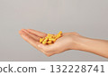 Close-up of a hand full of yellow capsules. Concept of vitamins, herbal supplements, turmeric curcumin, medication and daily healthcare routine. 132228741