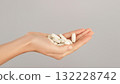 A close-up of a hand full of white pills. Conceptual ideas for vitamins, bone and joint supplements, medications, and daily self-care. 132228742