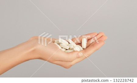 A close-up of a hand full of white pills. Conceptual ideas for vitamins, bone and joint supplements, medications, and daily self-care. A close-up of a hand full of white pills. Conceptual ideas for vitamins, bone and joint supplements, medications, and daily self-care. 132228742