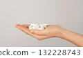 Hand holding a pile of white capsules on a neutral background with copy space. Concept of dietary supplements, vitamins and healthcare pills. 132228743