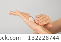 Close-up of female hands applying moisturizing cream on neutral background. Hygiene, Body care, and Skincare concept.  132228744