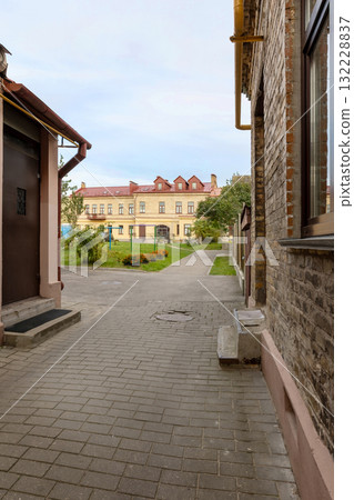 Old courtyard with paved walkway leading to historic residential building 132228837
