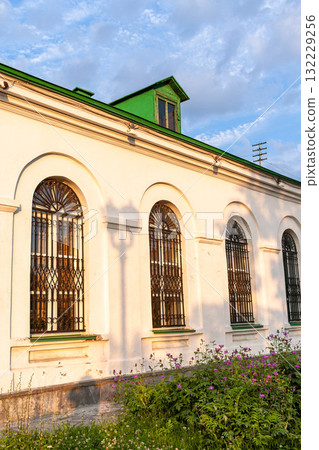 Architectural detail of a historic building with arched windows and vibrant green roof accents 132229256