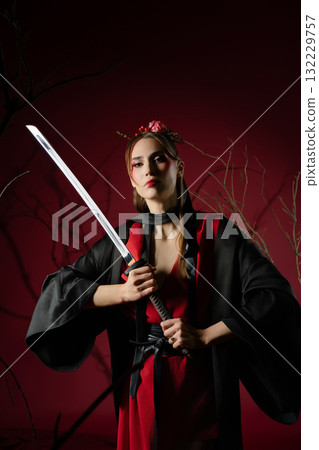 Woman in traditional Japanese dress poses with katana in a studio setting 132229757