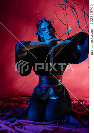 Woman in traditional Japanese dress posing elegantly in a studio with colorful lighting 132229760