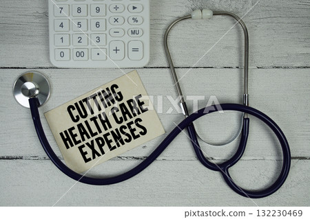 Cutting Health Care Expenses text with Stethoscope and calculator on wooden background 132230469