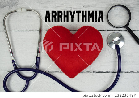 Arrhythmia text with Red heart, Magnifying glass and Medical Stethoscope on wooden background 132230487