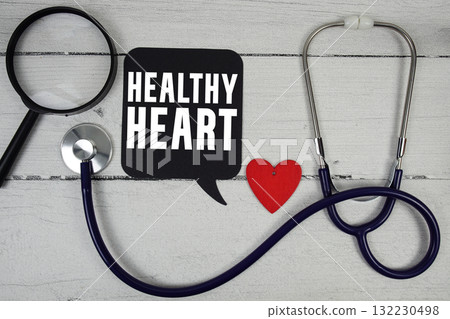 Healthy Heart text with Red heart, Magnifying glass and Medical Stethoscope on wooden background 132230498