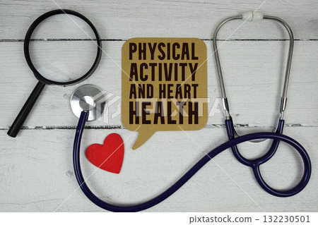 Physical Activity and Heart Health text with Red heart, Magnifying glass and Medical Stethoscope on wooden background 132230501