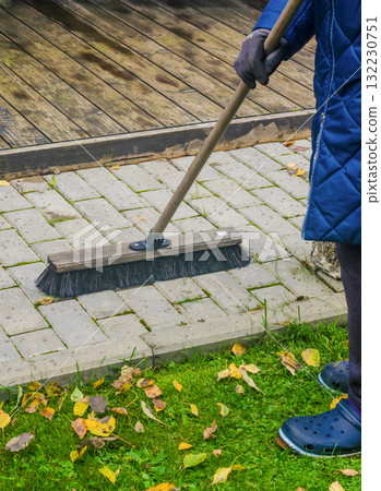 Person Sweeping Wet Pavement and Fallen Leaves with Large Outdoor Broom Person Sweeping Wet Pavement and Fallen Leaves with Large Outdoor Broom 132230751