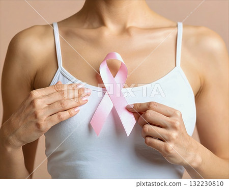 Woman Holding Pink Ribbon on Chest, Symbol of Breast Cancer Awareness 132230810