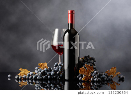 Bottle and glass of red wine with blue grapes on a black background. Bottle and glass of red wine with blue grapes on a black background. 132230864