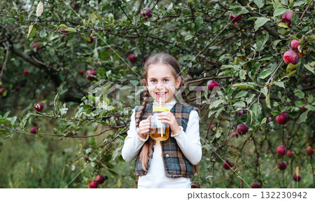 Harvesting apples in the garden. A little girl is having fun in apple orchard with red apple in her hands. 132230942