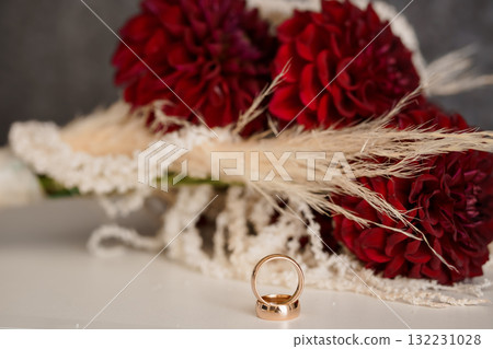Romantic Wedding Rings and Deep Red Dahlia Bouquet with Pampas Grass. Gold Bands, Floral Arrangement, Love, Commitment, Celebration Style. Romantic Wedding Rings and Deep Red Dahlia Bouquet with Pampas Grass. Gold Bands, Floral Arrangement, Love, Commitment, Celebration Style. 132231028