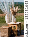 Bohemian Wedding Decor Scene with Pampas Grass, Rustic Wooden Furniture, Sheer Curtains and Summer Field Backdrop Natural Texture and Warm Tones 132231043