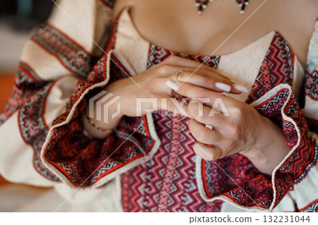 Intricate Embroidered Vyshyvanka Hands Clasping, Red and Cream Traditional Ukrainian Clothing, Delicate Jewelry, Close-Up Texture. 132231044