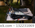 Outdoor Audio Setup with Mixer, Recorder, and Microphones on Wooden Table in Lush Green Forest Environment, Professional Recording. 132231069