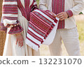 Authentic Ukrainian Couple in Traditional Vyshyvanka Embroidery Holding Cloth, Beige Linen, Red Accents, Cultural Heritage, Folk Costume, Close-Up Shot. 132231070