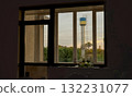 Window View of Water Tower at Sunset: Rustic Interior, Golden Light, Autumnal Trees, Nostalgic Atmosphere, Concrete Texture, Still Life Composition. 132231077