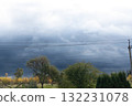 Dramatic Storm Clouds Over Trees and Power Lines Dark Blue Sky, Autumn Foliage, Rural Landscape, Ominous Weather, Atmospheric Perspective. 132231078