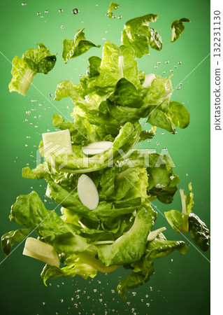vegetables flying in water splashes, salad and greens, on green background, fresh and healthy food 132231130
