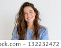 Young Woman With Long Hair Smiling Warmly Against a Light Background 132232472