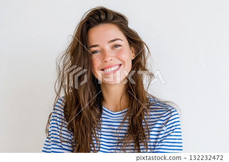 Young Woman With Long Hair Smiling Warmly Against a Light Background 132232472