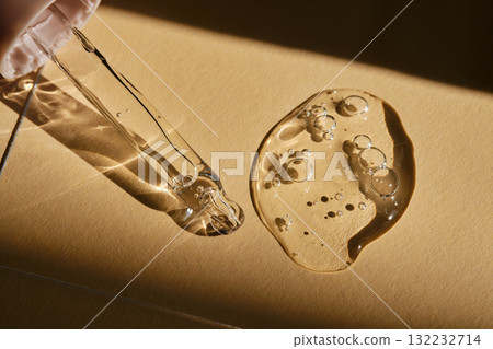 A pipette with cosmetic serum on a beige background. A pipette with cosmetic serum on a beige background. 132232714