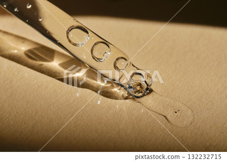 A pipette with cosmetic serum on a beige background. A pipette with cosmetic serum on a beige background. 132232715