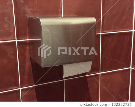 Stainless steel paper holder on tiled wall. Hygiene, minimalism, and restroom design in modern public space. 132232725