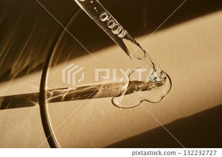 A pipette with cosmetic serum on a beige background. A pipette with cosmetic serum on a beige background. 132232727