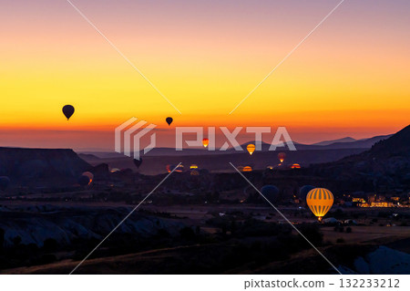 Hot air balloon flying over rocky landscape at sunrise in Cappadocia. Turkey 132233212