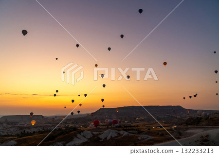 Hot air balloon flying over rocky landscape at sunrise in Cappadocia. Turkey 132233213