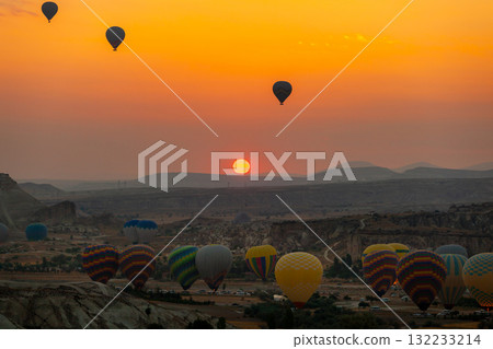 Hot air balloon flying over rocky landscape at sunrise in Cappadocia. Turkey Hot air balloon flying over rocky landscape at sunrise in Cappadocia. Turkey 132233214