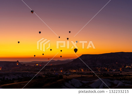 Hot air balloon flying over rocky landscape at sunrise in Cappadocia. Turkey Hot air balloon flying over rocky landscape at sunrise in Cappadocia. Turkey 132233215
