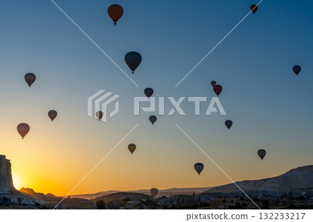 Hot air balloon flying over rocky landscape at sunrise in Cappadocia. Turkey Hot air balloon flying over rocky landscape at sunrise in Cappadocia. Turkey 132233217