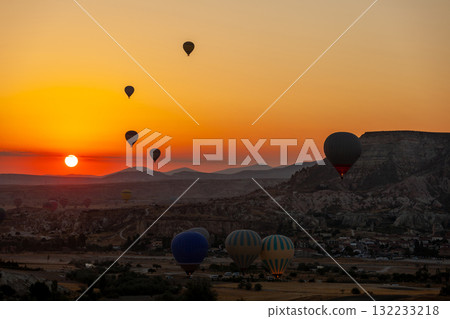 Hot air balloon flying over rocky landscape at sunrise in Cappadocia. Turkey Hot air balloon flying over rocky landscape at sunrise in Cappadocia. Turkey 132233218