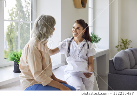 Senior patient in medical clinic talking with female young friendly nurse. Doctor support concept. 132233487