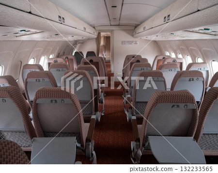 airplane interior scene, symmetrical airplane cabin layout with ambiance and seating, interior of airplane showing economy class with symmetrical seating arrangement and lighting ambiance 132233565