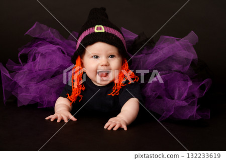 Smiling baby in Halloween witch costume with purple tulle skirt and orange yarn hair 132233619
