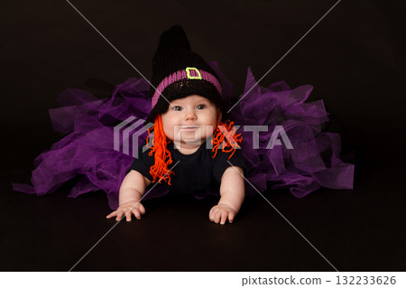 Smiling baby in Halloween witch costume with purple tulle skirt and orange yarn hair 132233626