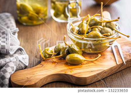 Pickled capers berries on wooden cutting board. 132233650